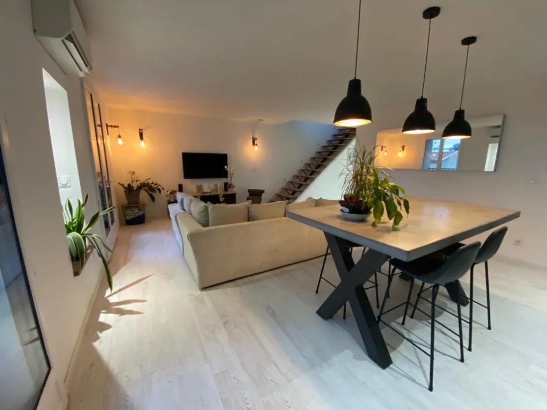 Séjour et salle à manger rénovés : parquet clair, table haute et suspensions noires
